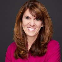 Headshot of a brunette woman in a pink shirt.